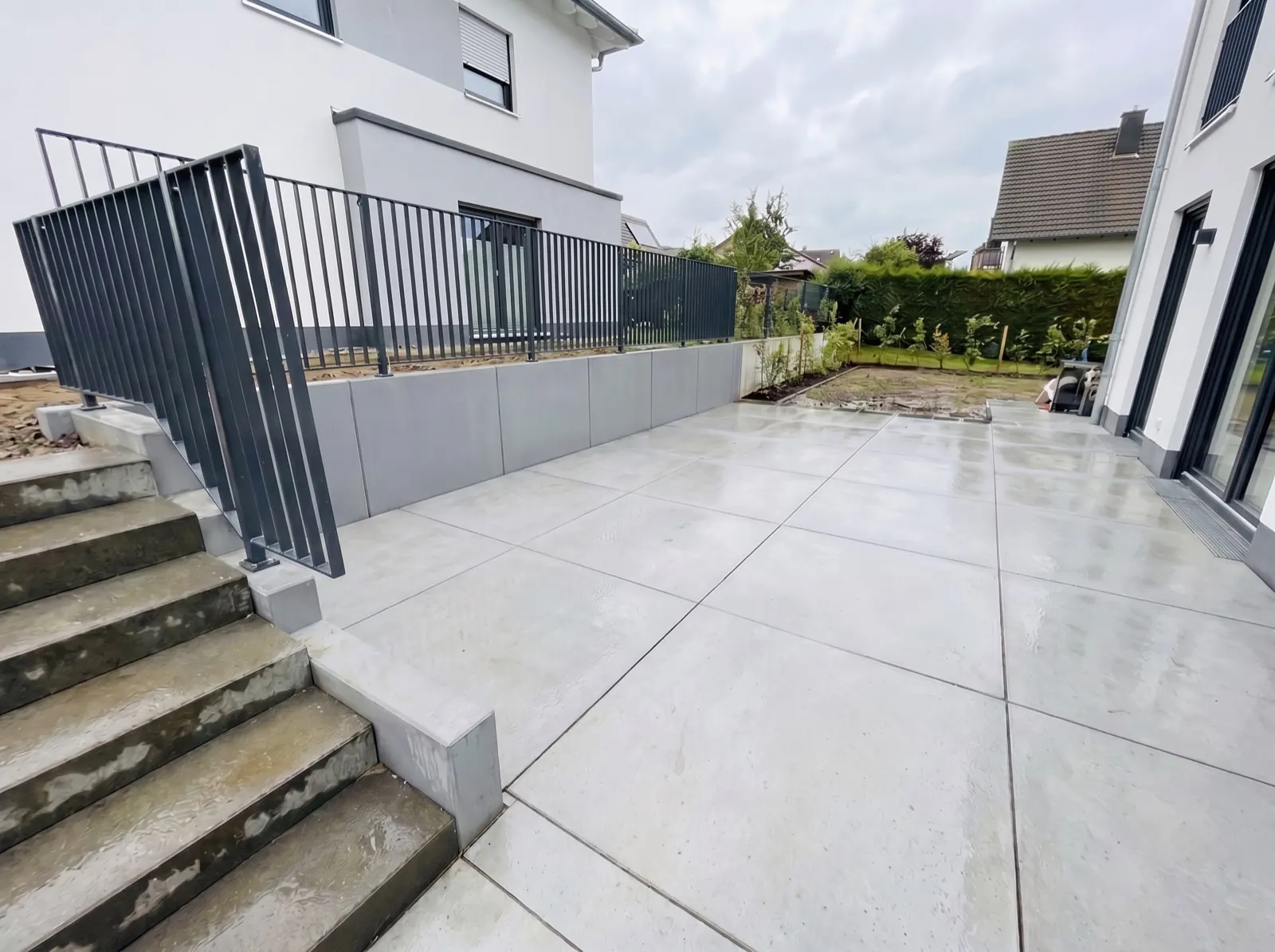 Neu gestaltete Terrassenanlage mit frischem Pflaster, L-Steinen und neuem Zaunsystem